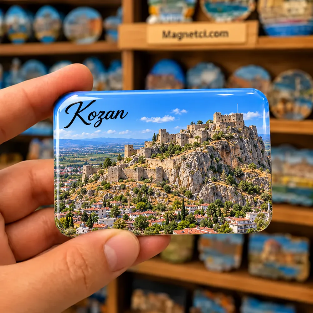 Adana Kozan Kalesi'nin kayalık tepedeki surları ve ilçe manzarası temalı elde tutulan parlak epoksi souvenir magnet